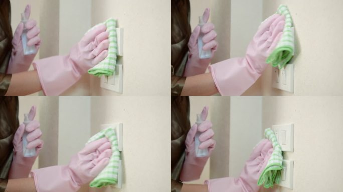 恐慌的亚洲妇女戴着手套喷洒酒精清洁电灯开关和门把手，以防冠状病毒。