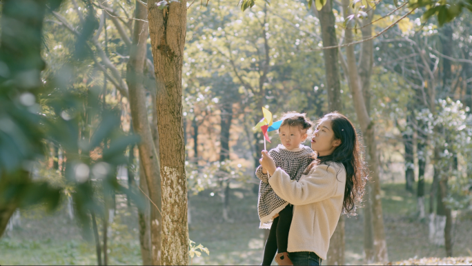 年轻妈妈带孩子在公园玩耍 树林