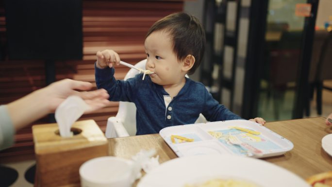亚洲男婴在餐厅与家人相处愉快。
