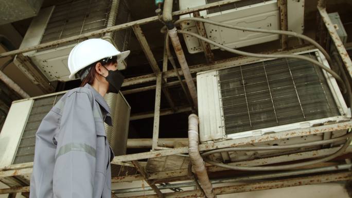 亚洲女技术员检查员检查大楼内的空调泄漏情况。工程师女性触摸