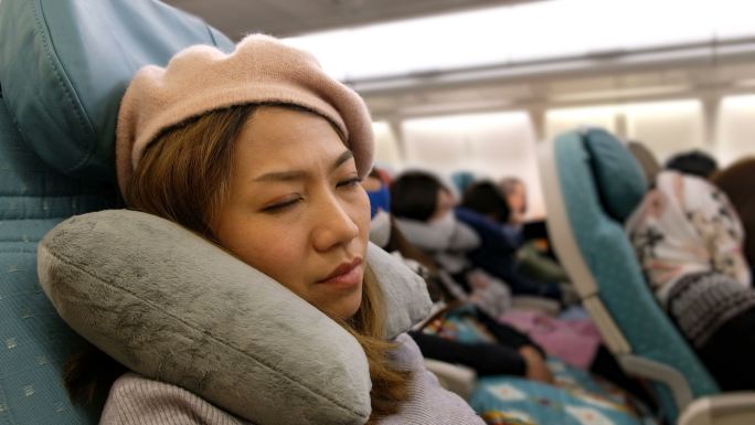 4K镜头：一名亚洲女子在飞机上睡着了。长途作战感到厌倦