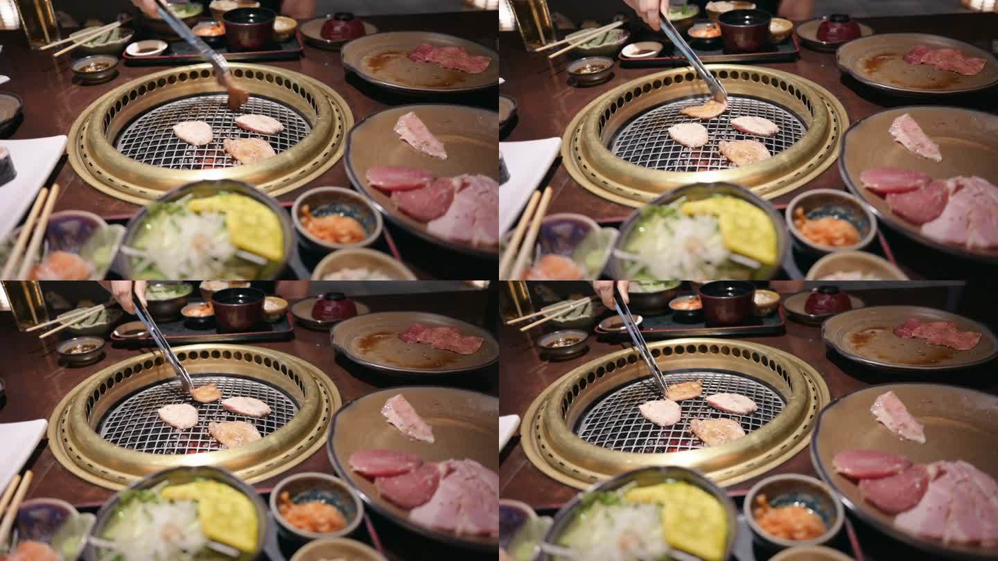 一位身材矮小的亚洲年轻女性在餐厅里吃着传统的日式牛肉烧烤“Yakiniku”，并将生牛肉片放在木炭烤
