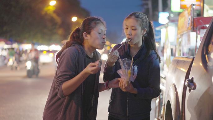 斯洛莫-亚洲朋友喜欢在夜市上吃烤鱿鱼。泰国街头美食。