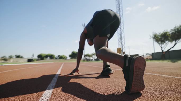 运动员处于起跑姿势，准备在体育中心或体育场的跑道上跑步。健壮、活跃、健壮的男子，准备参加奥运会比赛和