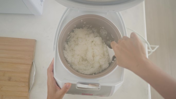 无法识别的日本女性在电饭锅里煮米饭