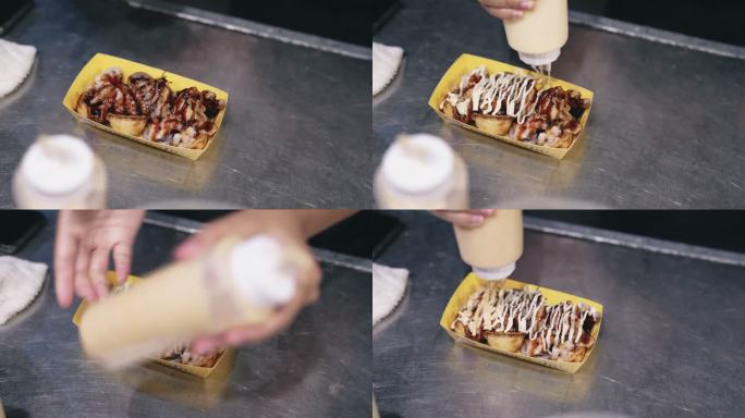 亚洲夜市小贩把酱汁放在煮熟的Takoyaki上。