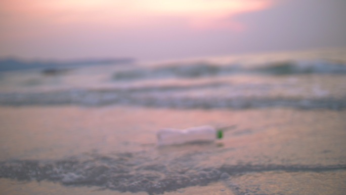 年轻女子在海滩上捡塑料瓶，回收概念
