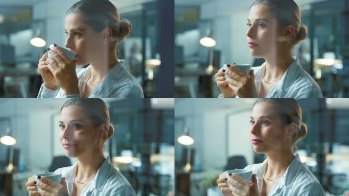 一位年轻漂亮的企业女商人在办公室里喝着茶或咖啡，透过玻璃墙望着。自信的女性商业专业人士在办公室里看起