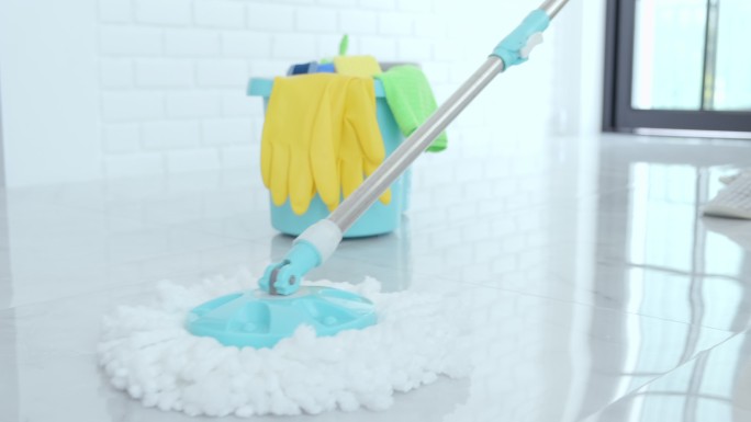 妻子的家政和清洁理念，戴着蓝色橡胶手套的快乐年轻女人在家里清洁地板时用拖把擦拭灰尘