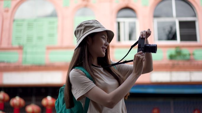 亚洲年轻女性背包客带着快乐的情感表达旅行时使用相机到摄影地点，在夏季生活方式度假时独自旅行。