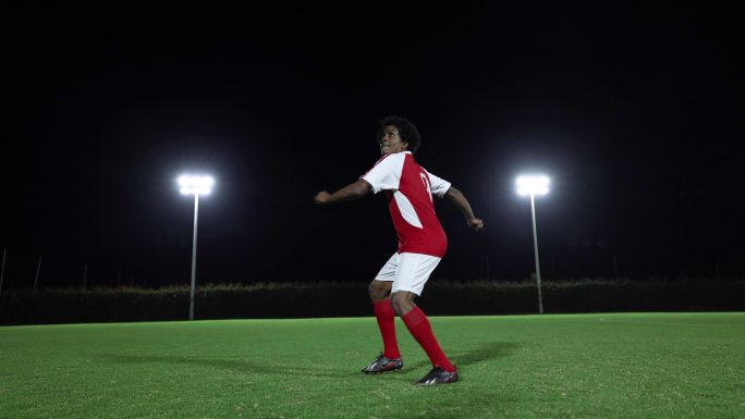 强大的足球运动员在夜间比赛时在球场上踢球