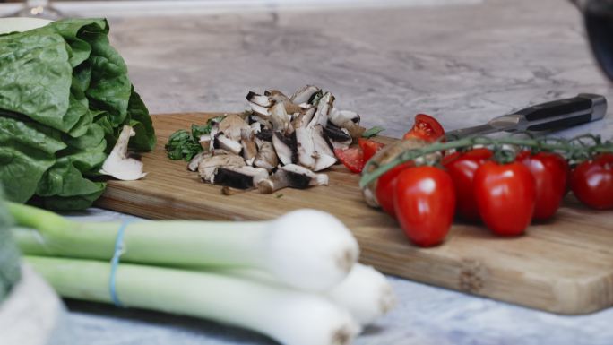 切菜板上的新鲜番茄、蘑菇和韭菜