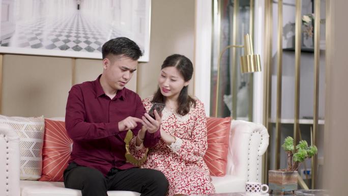 幸福生活年轻夫妻在沙发上玩手机分享新鲜事