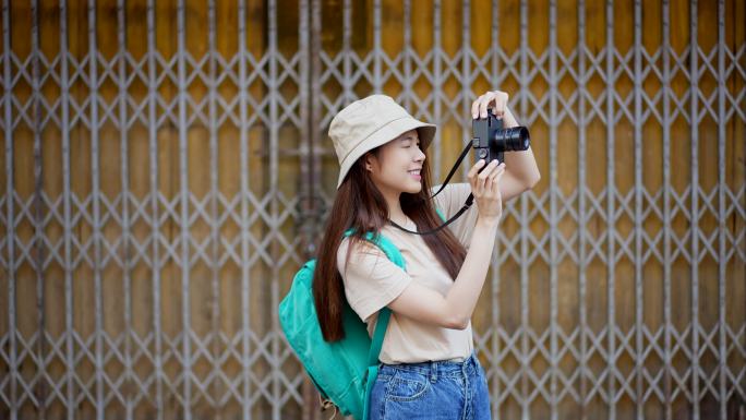 亚洲年轻女性背包客带着快乐的情感表达旅行时使用相机到摄影地点，在夏季生活方式度假时独自旅行。