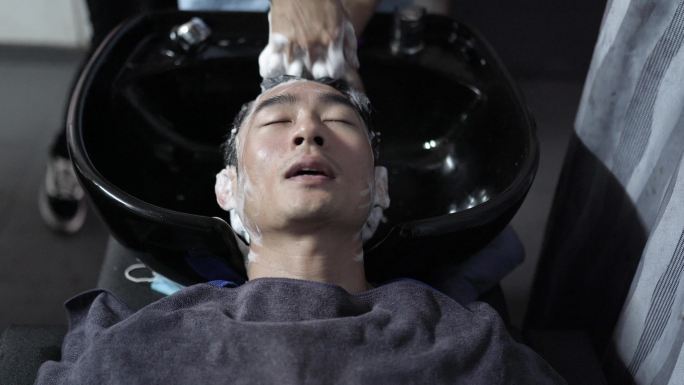 亚裔中国发型师在发廊为顾客洗头