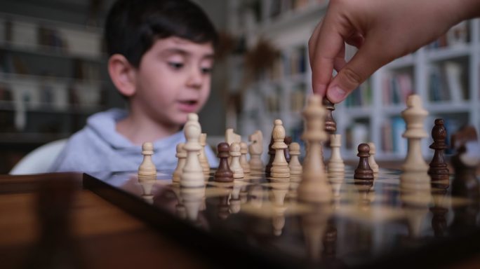 父子俩在家一起下棋。家人在家。