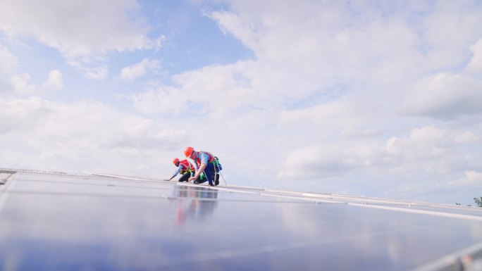 技术人员在工厂屋顶安装和维护太阳能电池板。