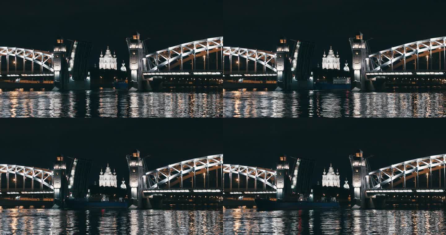 圣彼得堡彼得大帝的一座开放式吊桥，夜晚灯光明媚，一艘驳船穿过
