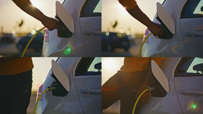 日落时分，一个无法辨认的年轻人在停车场给他的电动车充电
