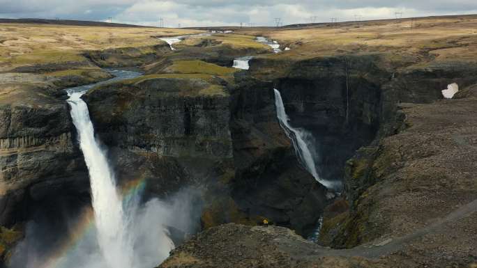 男女游客在冰岛欣赏彩虹瀑布谷美景的鸟瞰图