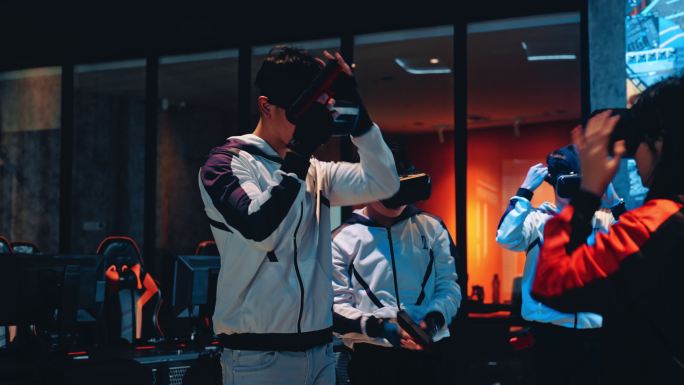 2支亚洲电子竞技队戴着VR眼镜准备在舞台上进行VR射击视频游戏，在总决赛中相互竞争