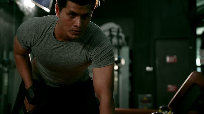 亚洲肌肉运动员锻炼，在健身房锻炼。健美运动员男子举重哑铃有益健康。