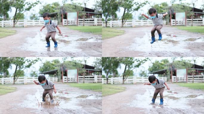 一个男孩穿着雨靴在泥泞的水坑里跳跃，发出巨大的水花