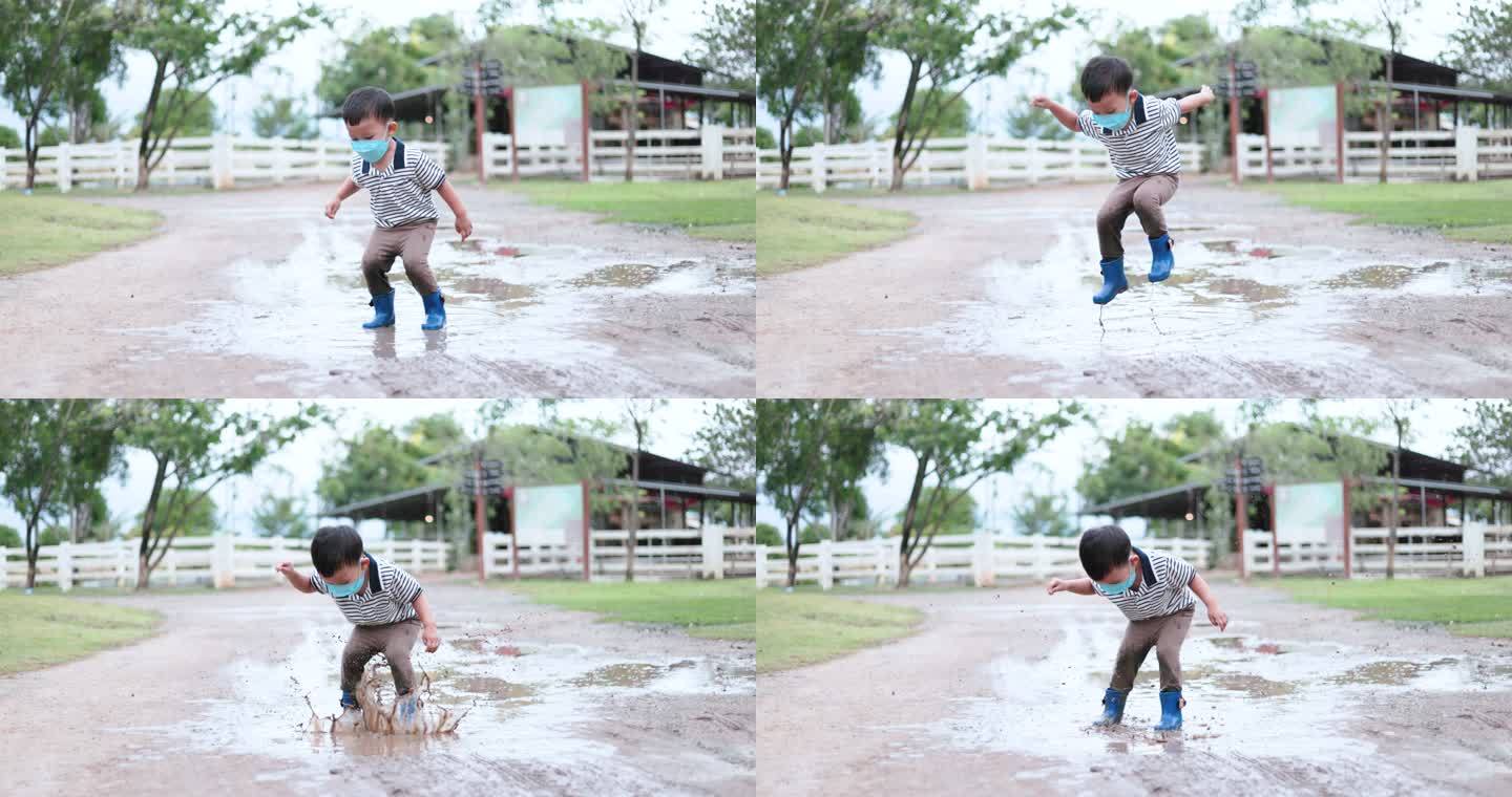 一个男孩穿着雨靴在泥泞的水坑里跳跃，发出巨大的水花