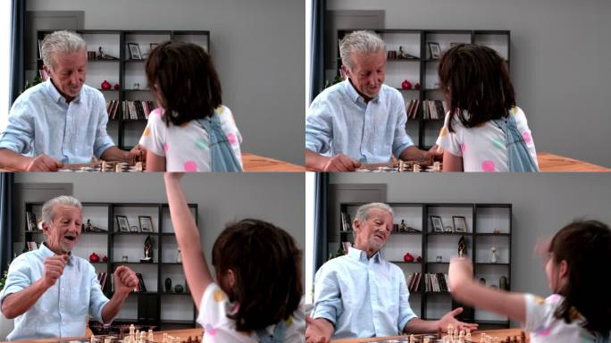 一位开朗的爷爷正和他的小孙女下棋，一起在家度过美好时光