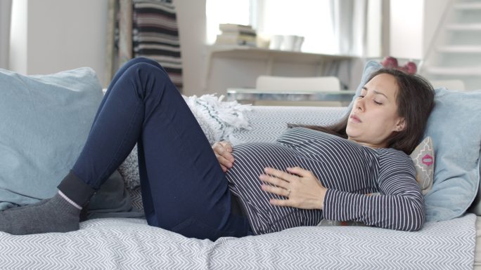孕妇躺在沙发上时呼吸沉重，疼痛难忍