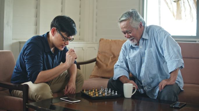 亚洲老父亲和小儿子在家一起下棋