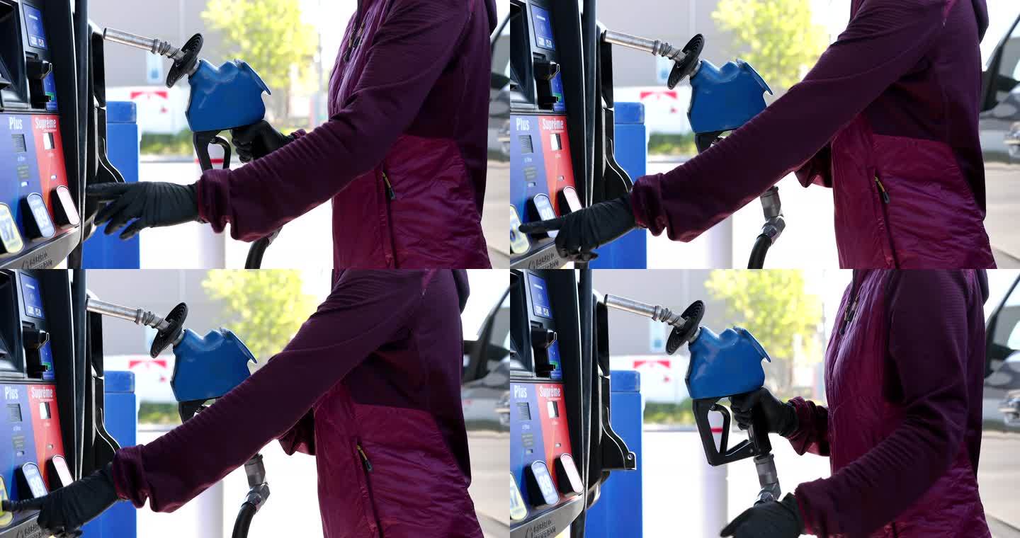 新冠肺炎期间，一名妇女戴着防护手套在加油站给汽车加油