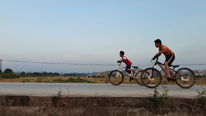 乡村村道骑自行车的男孩骑车玩车技的小男孩