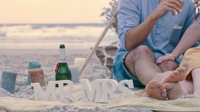 一对面目全非的情侣在海滩上求婚后喝着香槟。一对热恋中的男女用葡萄酒庆祝订婚的特写镜头
