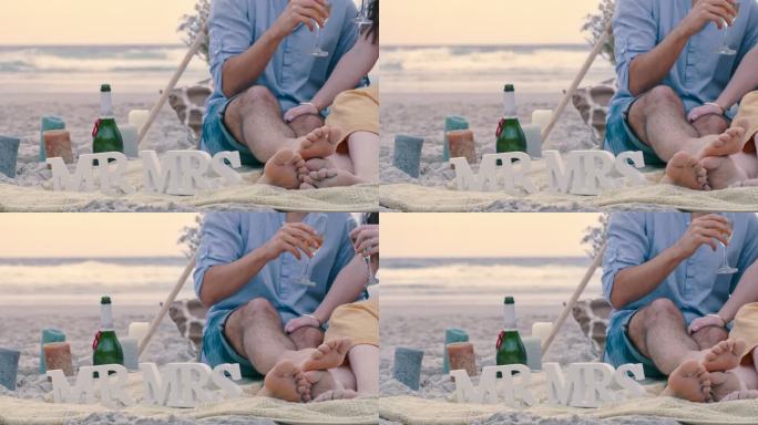 一对面目全非的情侣在海滩上求婚后喝着香槟。一对热恋中的男女用葡萄酒庆祝订婚的特写镜头
