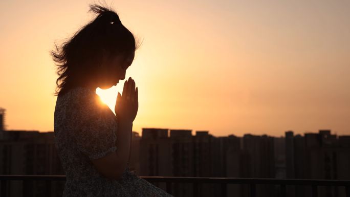 女人用阳光祈祷女人用阳光祈祷剪影日落黄昏