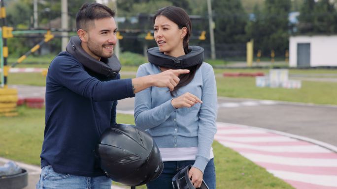 一个快乐的男人在一个手推车赛道上向她的女性朋友解释一些事情，然后击掌