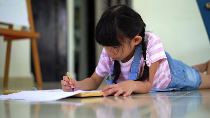 年轻女孩用蜡笔在画板上写生