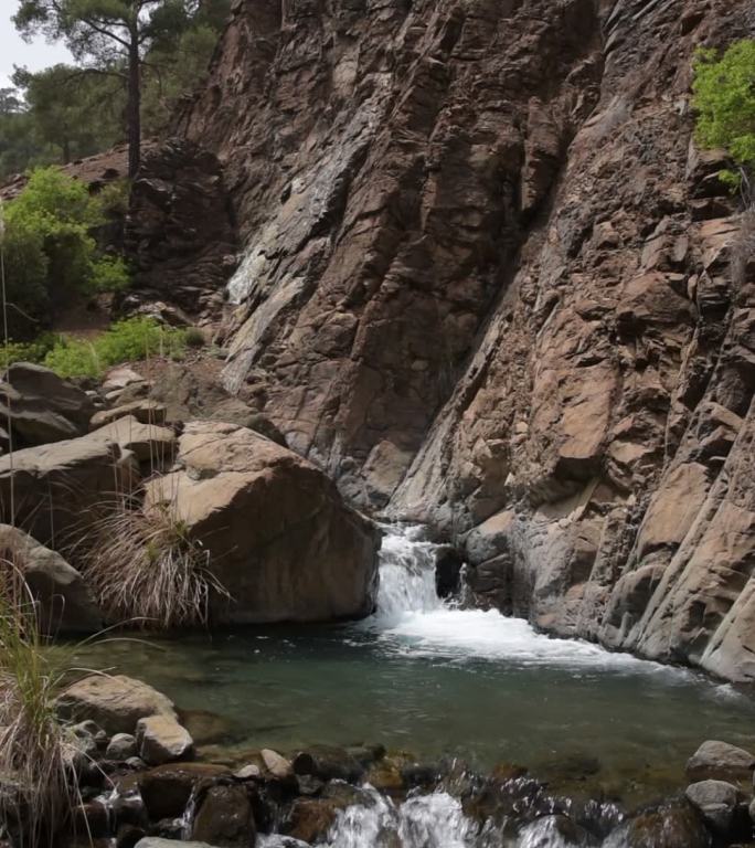 清澈的水流顺着小瀑布倾泻而下，更大的落差落入悬崖边缘的深岩池