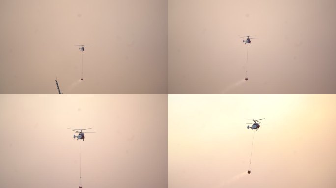 空中消防飞行直升机，在黄色多云的天空背景下带着水篮子。