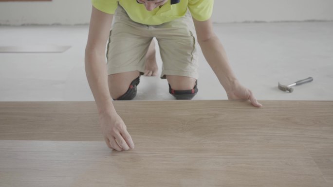 男子安装新的木质层压木地板，家居装修，房屋翻新项目概念