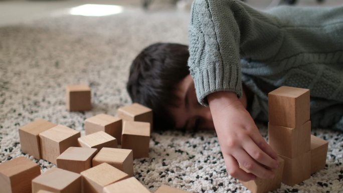 坐在地板上的小孩。漂亮的男孩在家玩木块
