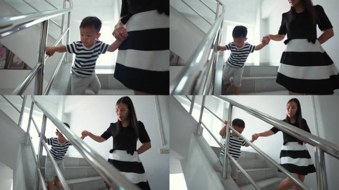 母亲牵着蹒跚学步的男孩的手走在楼梯上