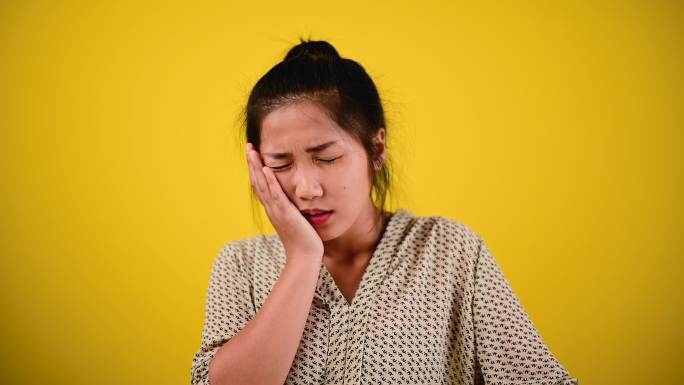 严重的牙痛亚洲女性有牙痛、疼痛、疼痛、受伤、牙齿、肿胀的脸颊和严重的内部烧灼感。牙套和智齿发炎患者的