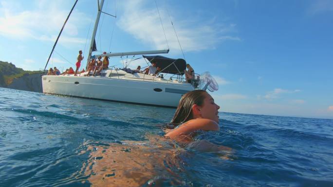 SLO MO POV年轻女子在海里朝船游得很开心