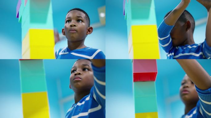 非洲黑人儿童的低角度镜头，一个7岁的男孩专注于彩色塑料积木的连接，高达头顶，并保护它在客厅里不会倒塌