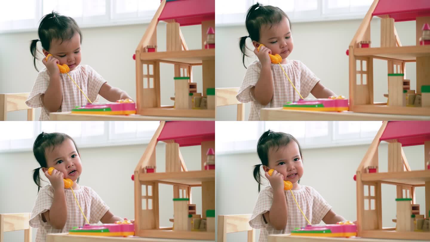 亚洲女婴在家里的游戏室里玩手机玩具