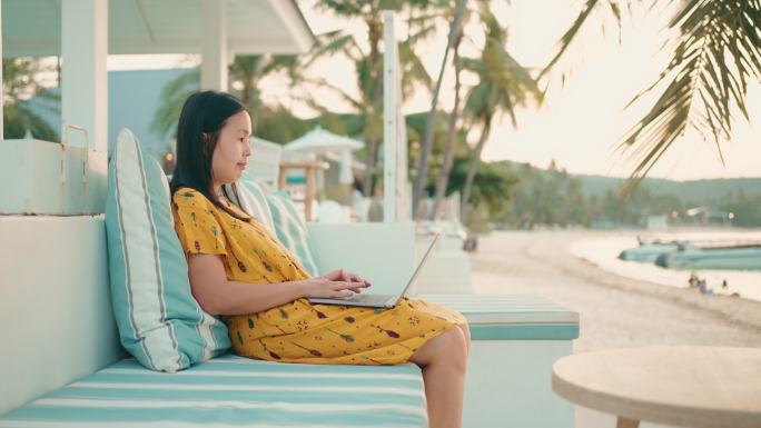自由职业者在海滩旅行时使用笔记本电脑。