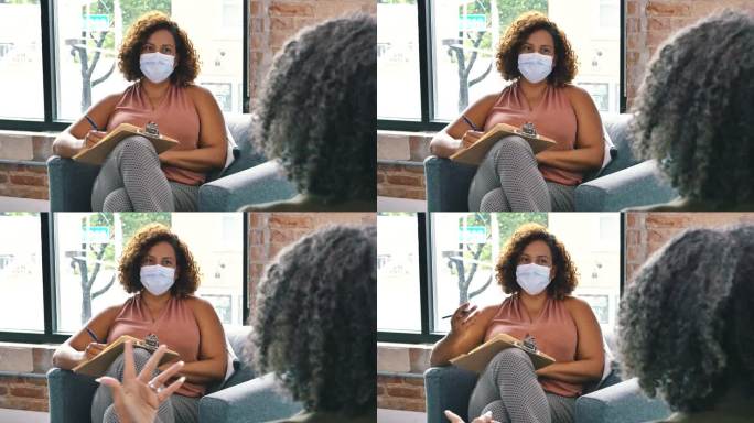 女性治疗师在新冠肺炎危机期间为患者提供咨询时戴口罩