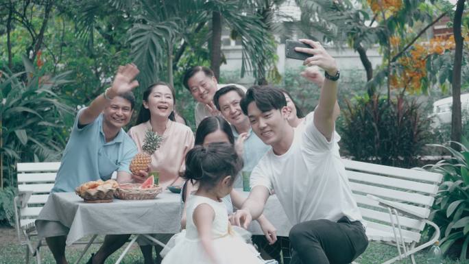 视频会议问候：泰国家庭在后院前举行烧烤派对后用手机自拍
